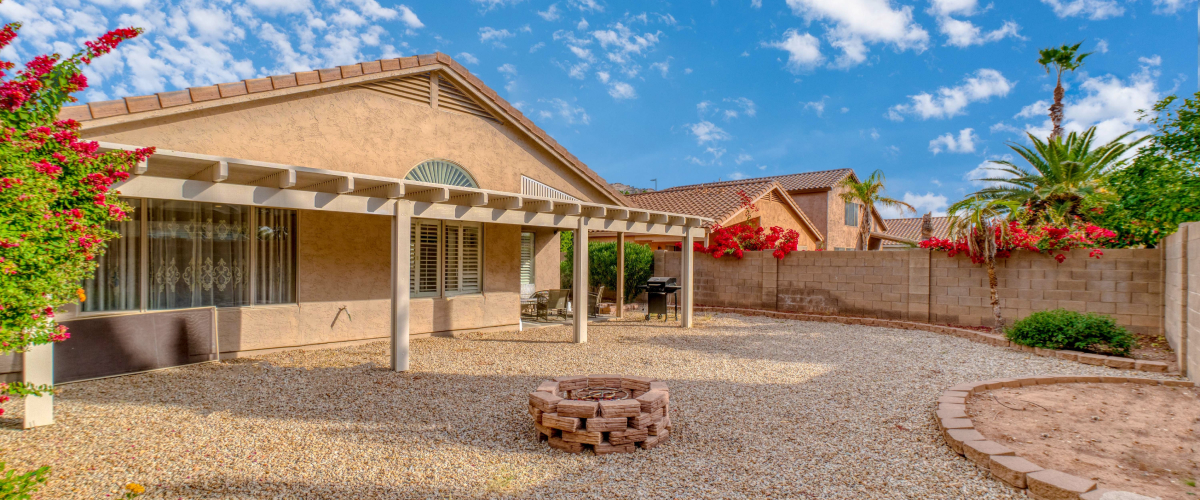 The backyard of a home in Arizona with a fire pit and a stone lawn.